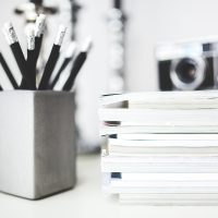 编辑部成员在深色办公桌前对着双屏整理建站流程稿，屏幕上是栏目结构草图，环境安静光线偏冷